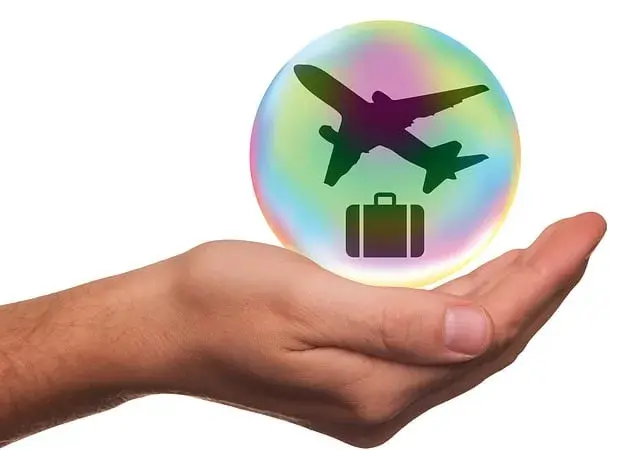 Hand holding a sustainable globe with transport and suitcase
